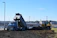 A rugged dump truck unloading gravel at a residential construction site under a clear sky.