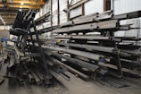 a large pile of steel beams in a warehouse