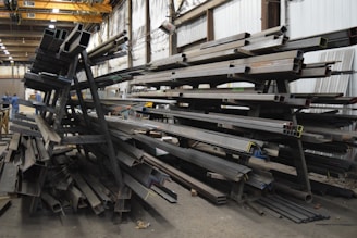 a large pile of steel beams in a warehouse