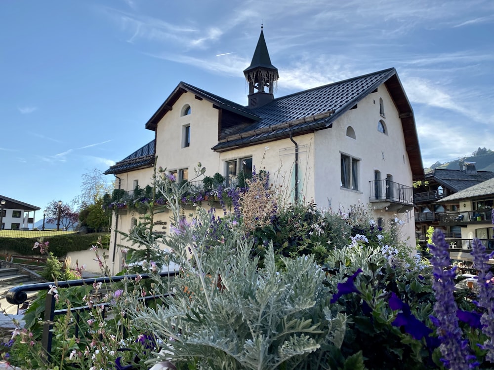 a white house with a tower and a garden in front of it