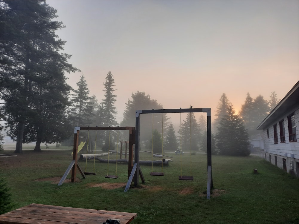 a wooden swing set in a grassy area next to a house