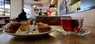 A cozy wooden table set with steaming cups of tea and freshly baked pies wrapped in rustic cloth.