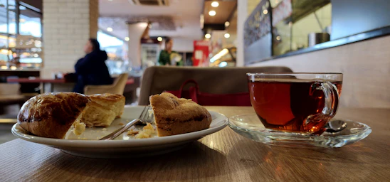 A cozy wooden table set with steaming cups of tea and freshly baked pies wrapped in rustic cloth.