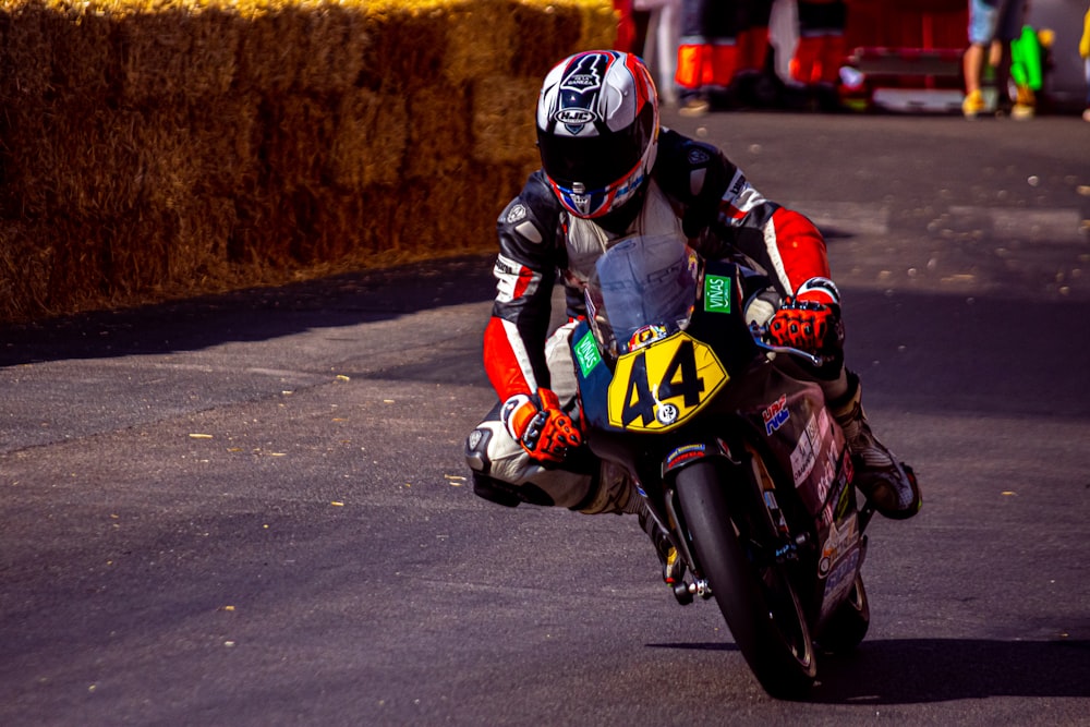 a man riding a motorcycle down a street next to hay bales