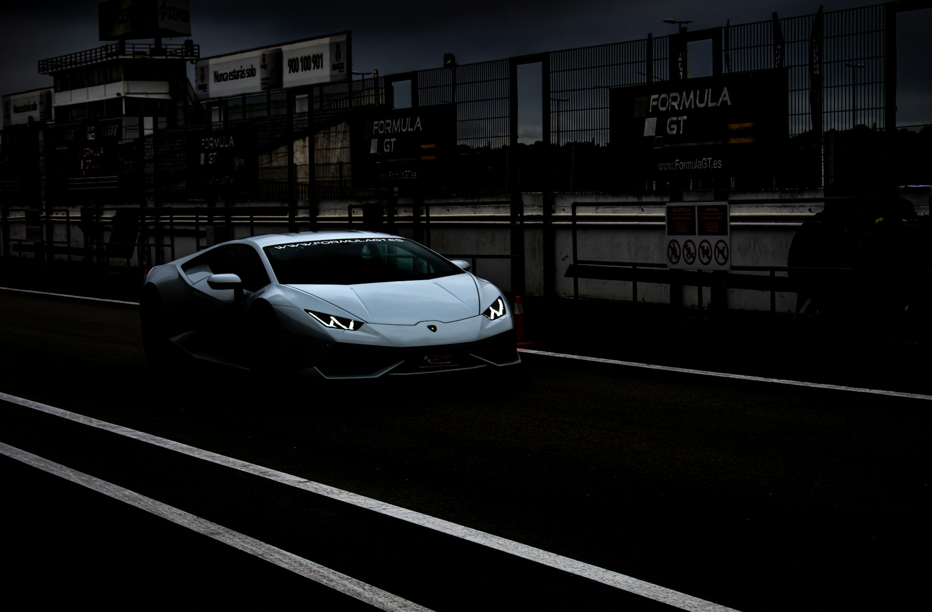 a white sports car driving down a street at night
