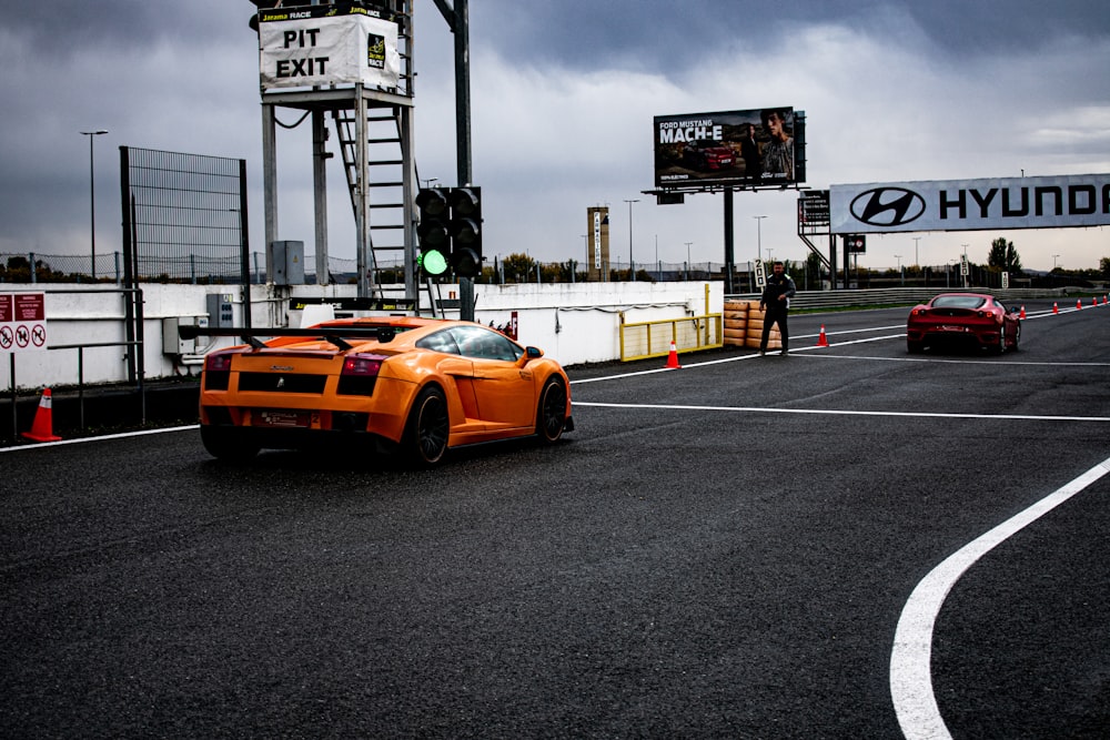 an orange sports car driving down a race track