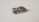 A small, detailed black toy car with gold and red stripes, placed on a light surface. It features branding and logo details that mimic a classic racing design.
