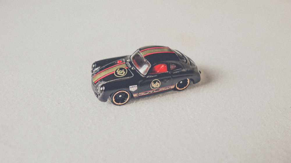 a black toy car sitting on top of a white surface