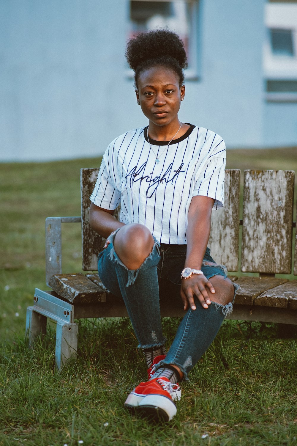 a woman sitting on a wooden bench in the grass