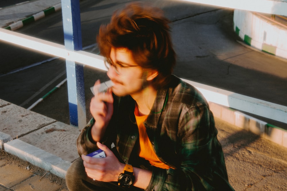 a man sitting on the ground smoking a cigarette