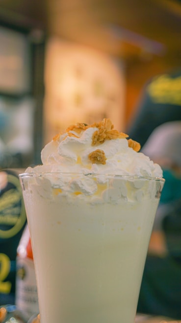 A creamy protein shake topped with sliced almonds and chia seeds on a rustic wooden table