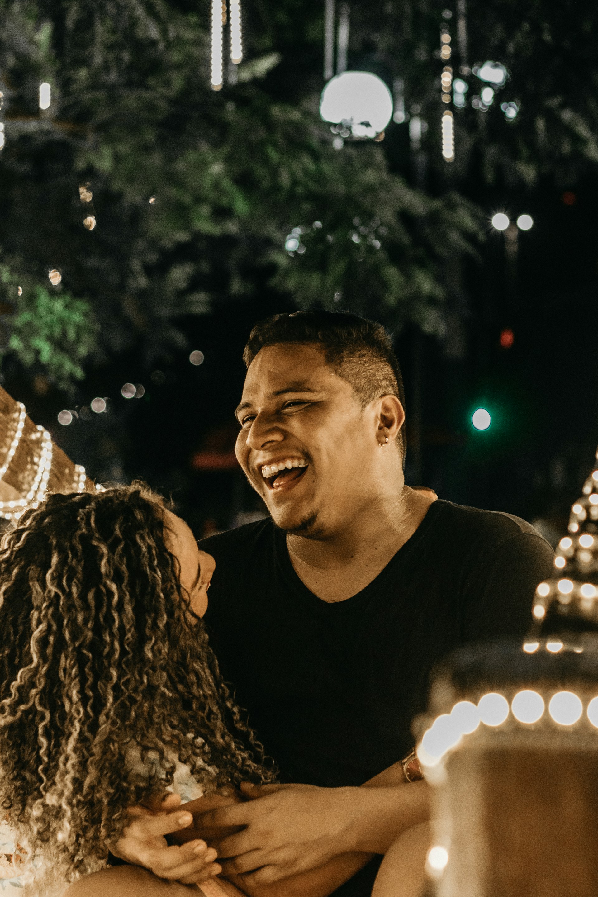 A joyful couple sharing a romantic moment during their first dance under soft fairy lights.
