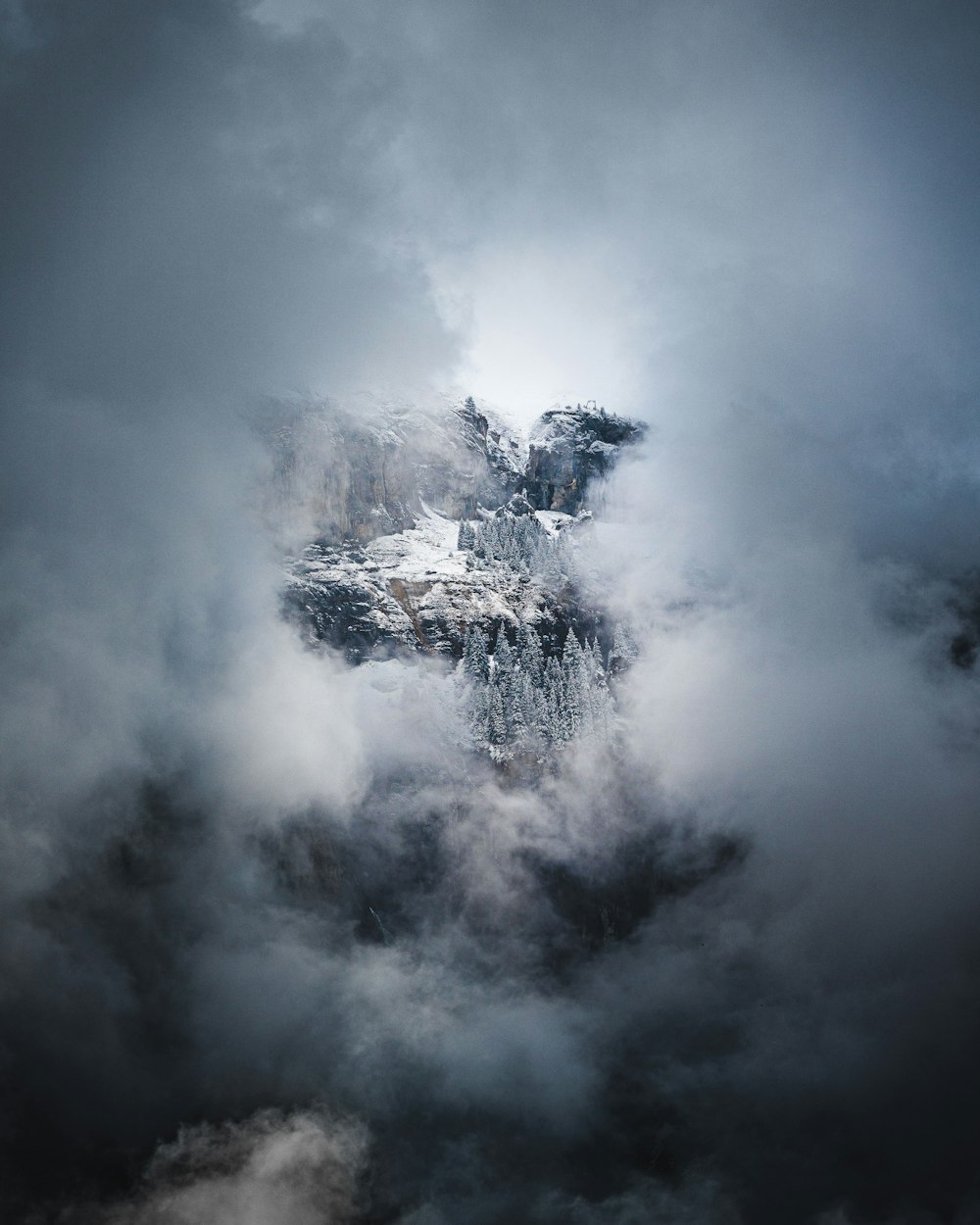 a large mountain surrounded by clouds in the sky