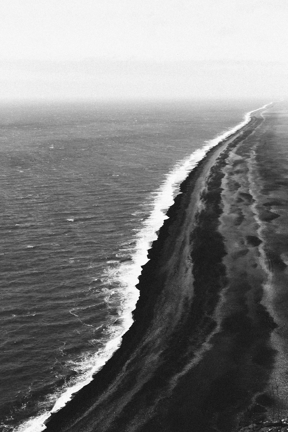 a black and white photo of a beach and ocean