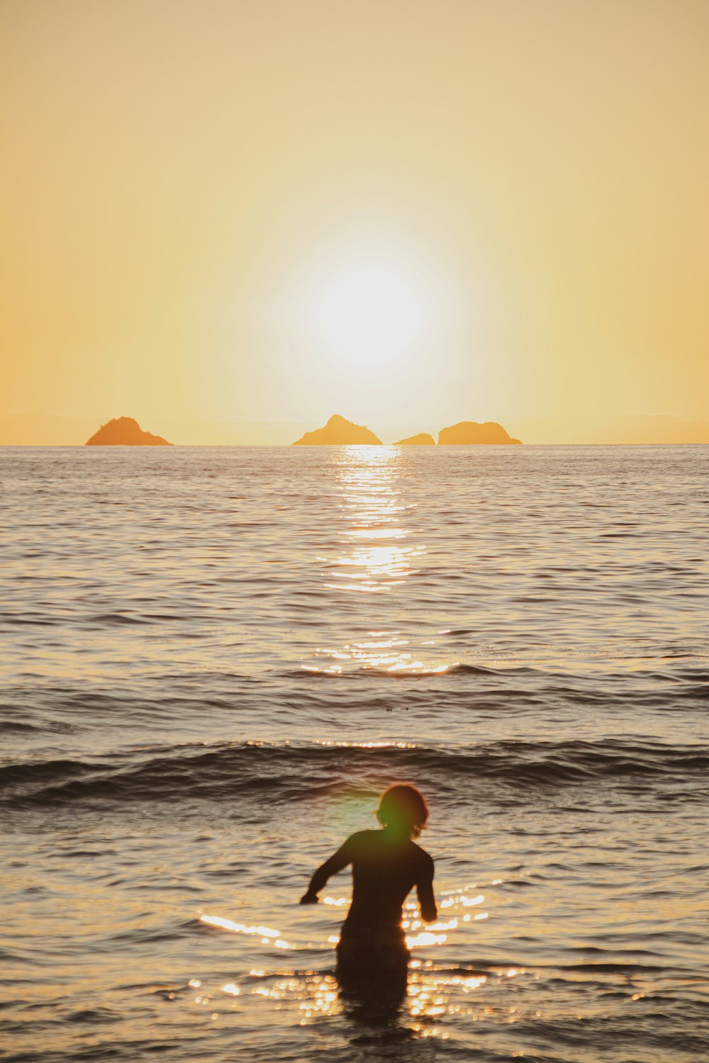 a person wading in the ocean at sunset