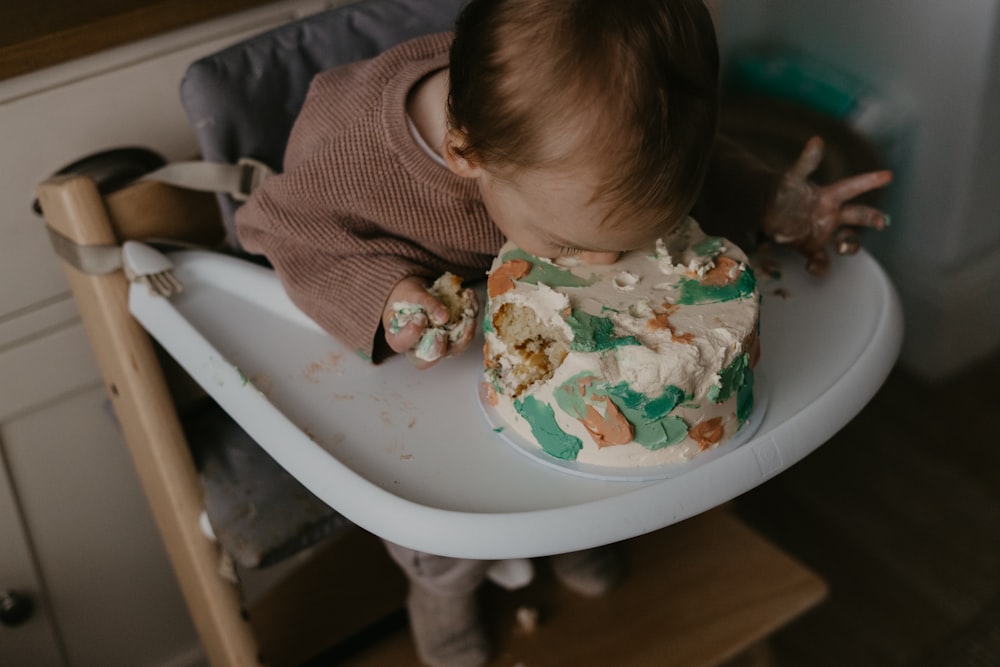 a baby in a high chair eating a cake