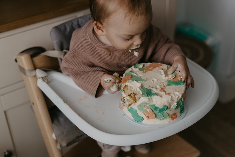 a baby in a high chair eating a cake