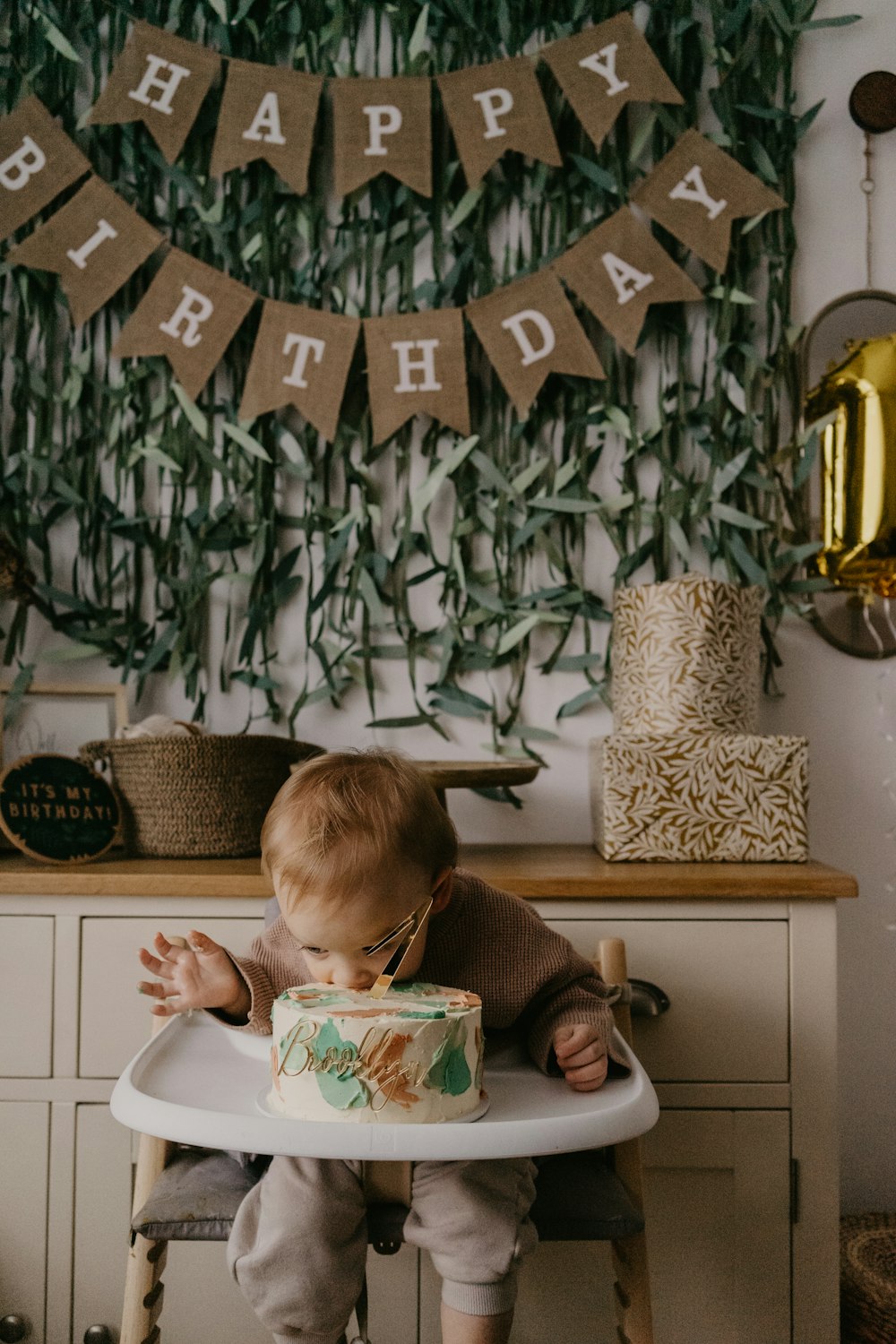 a baby sitting in a high chair with a birthday cake