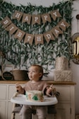 a baby sitting in a high chair with a birthday cake