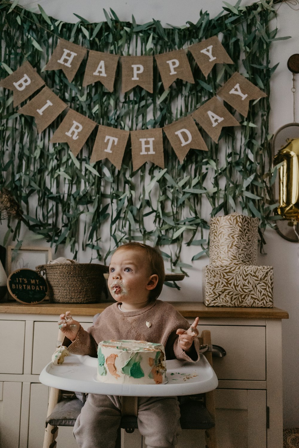 a baby sitting in a high chair with a birthday cake