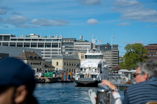 A panoramic view of a newly constructed ferry docked at a bustling harbor under clear skies.