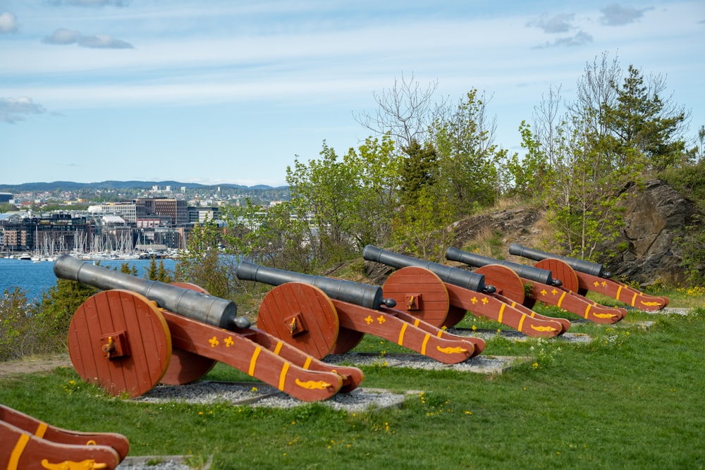 a row of wooden cannon guns sitting on top of a lush green field