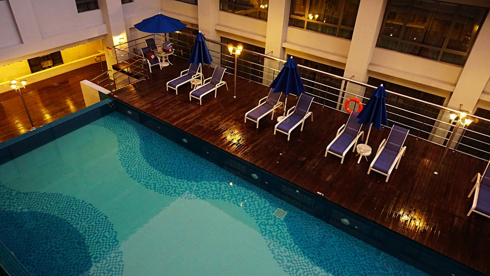 a swimming pool with lounge chairs and umbrellas