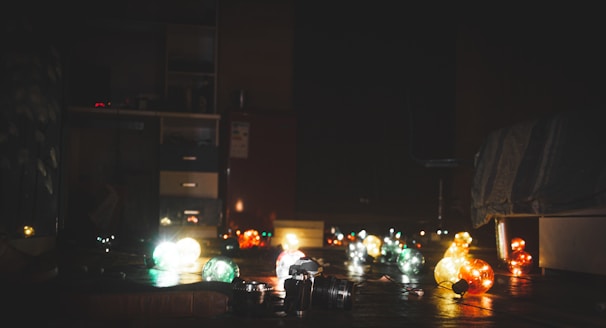 Close-up of colorful K-pop photo cards and lightsticks glowing softly in a cozy room.