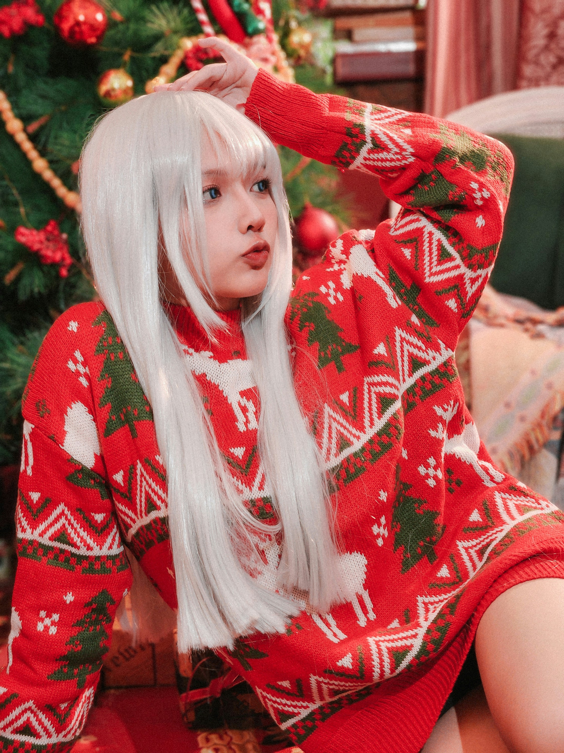Seorang wanita dengan rambut putih panjang mengenakan sweter Natal merah