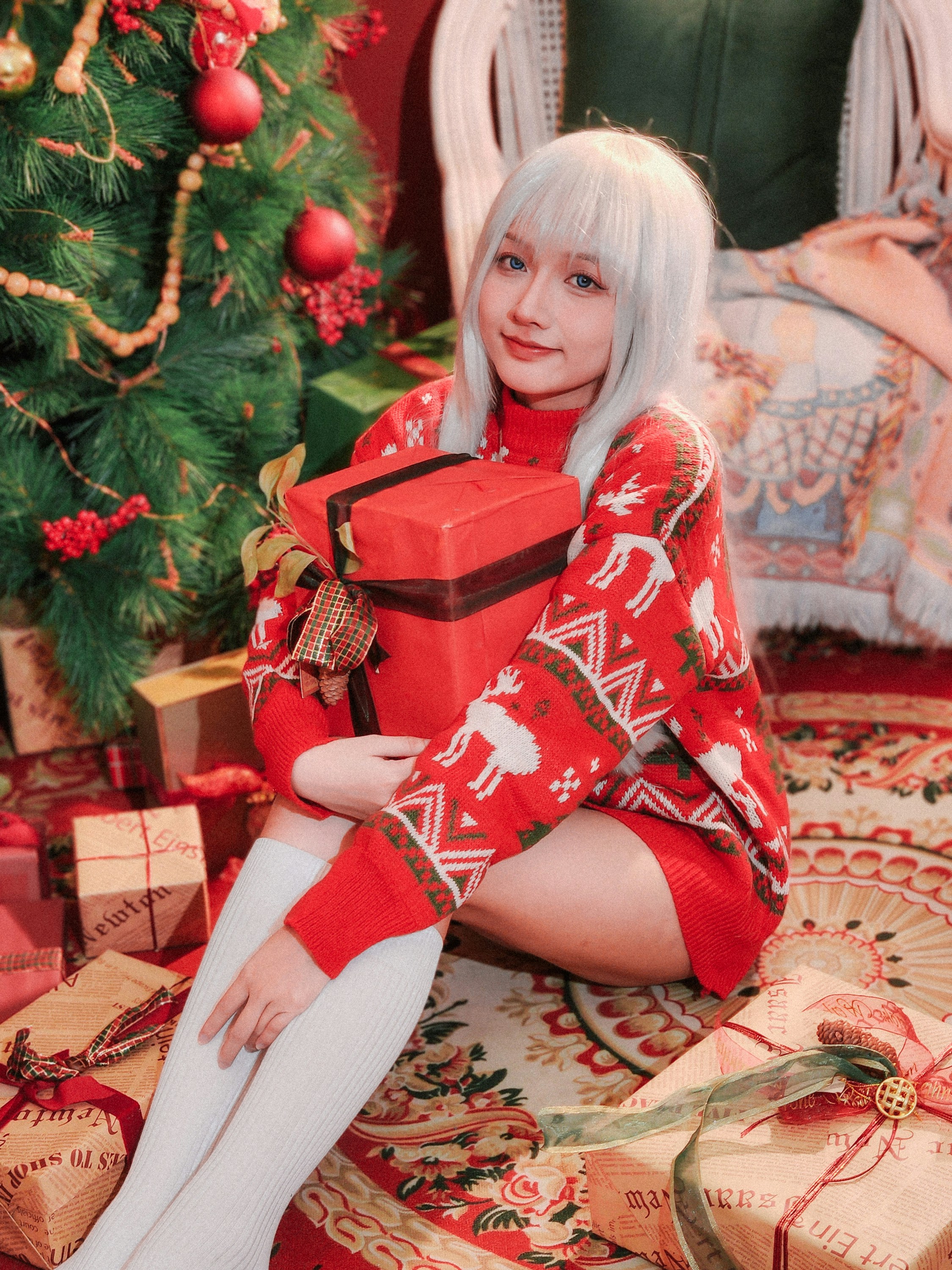 Seorang wanita duduk di lantai dengan hadiah Natal