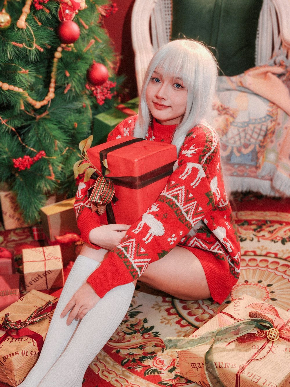 a woman sitting on the floor with a christmas present