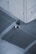 A security camera is mounted on the corner of a concrete ceiling. The ceiling appears to have a grid-like metal mesh and industrial design elements.