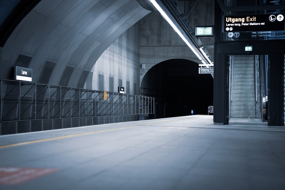 a tunnel with a metal railing and a light at the end