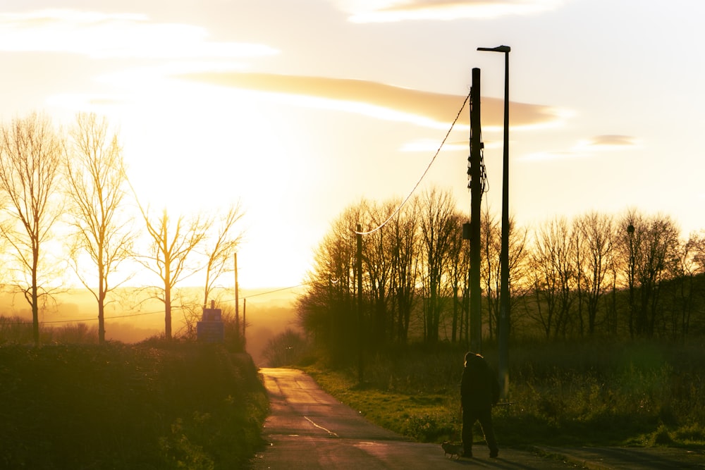 a person walking down a road at sunset