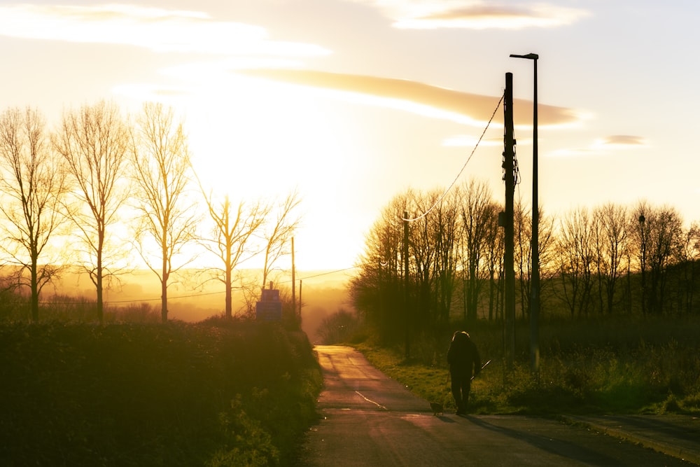 a person walking down a road at sunset