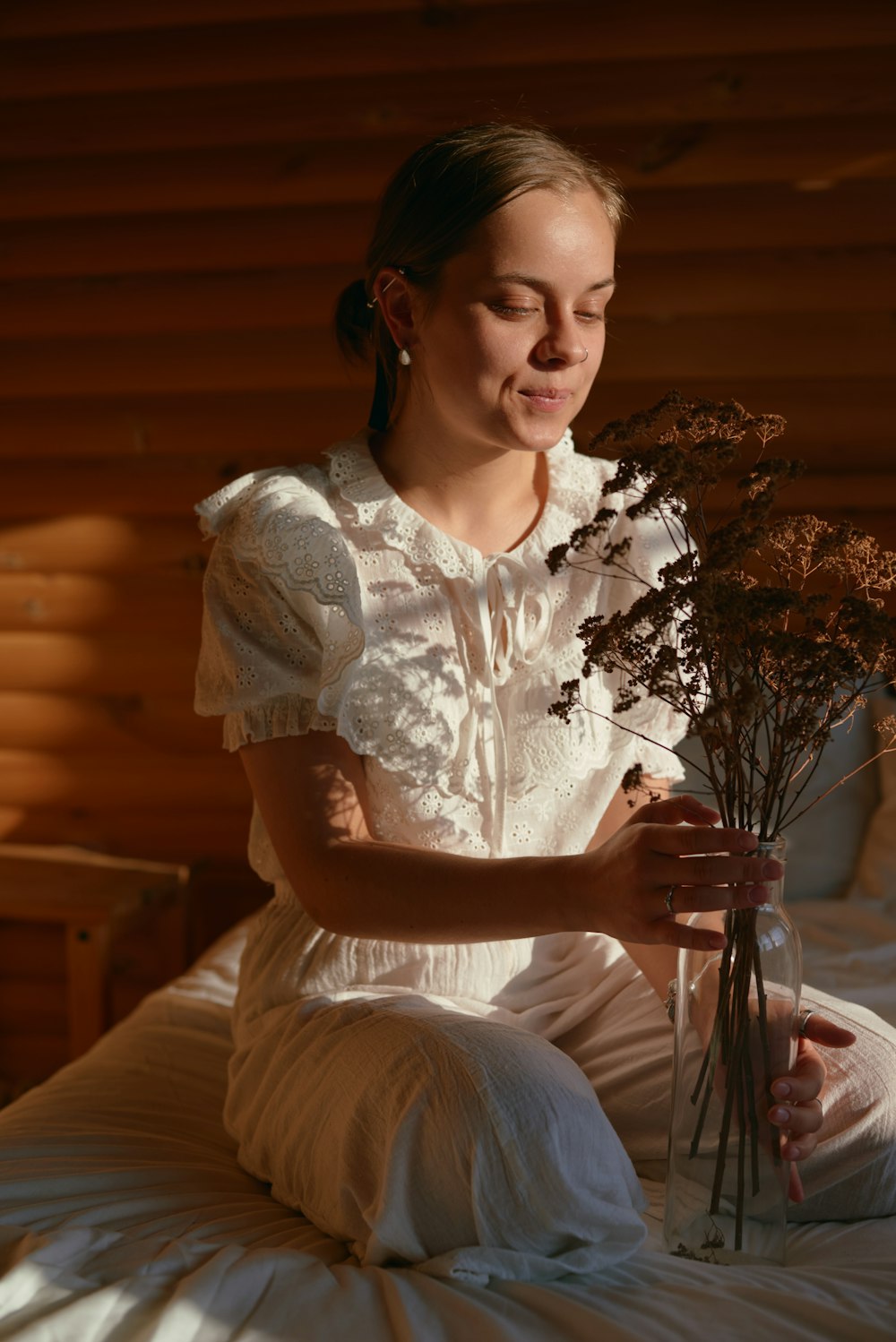 a woman sitting on a bed holding a bouquet of flowers