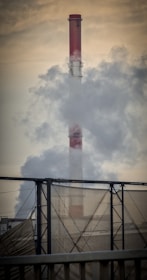 Outdoor industrial chimney emitting smoke with environmental monitoring equipment nearby.