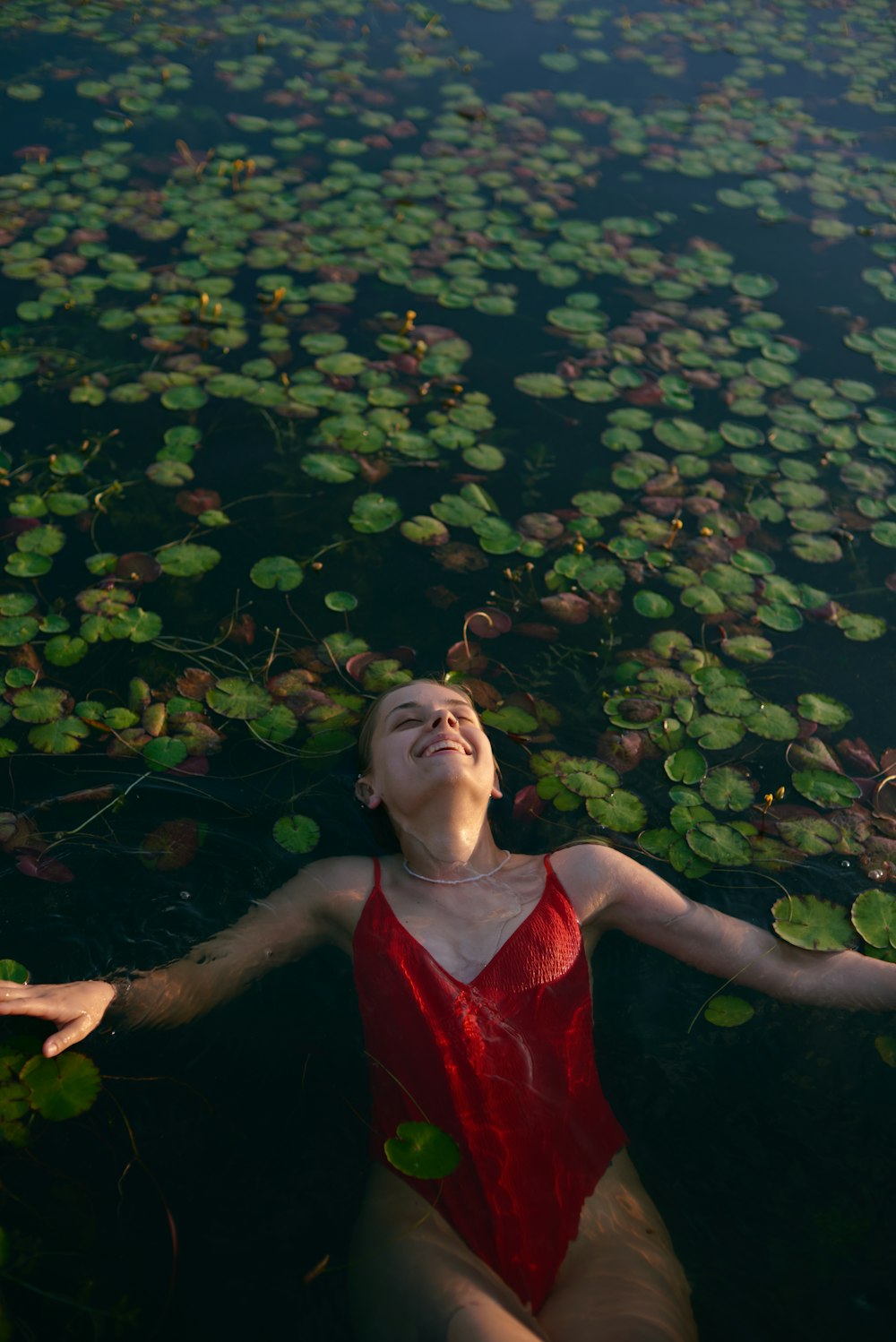 a woman floating in a body of water surrounded by lily pads