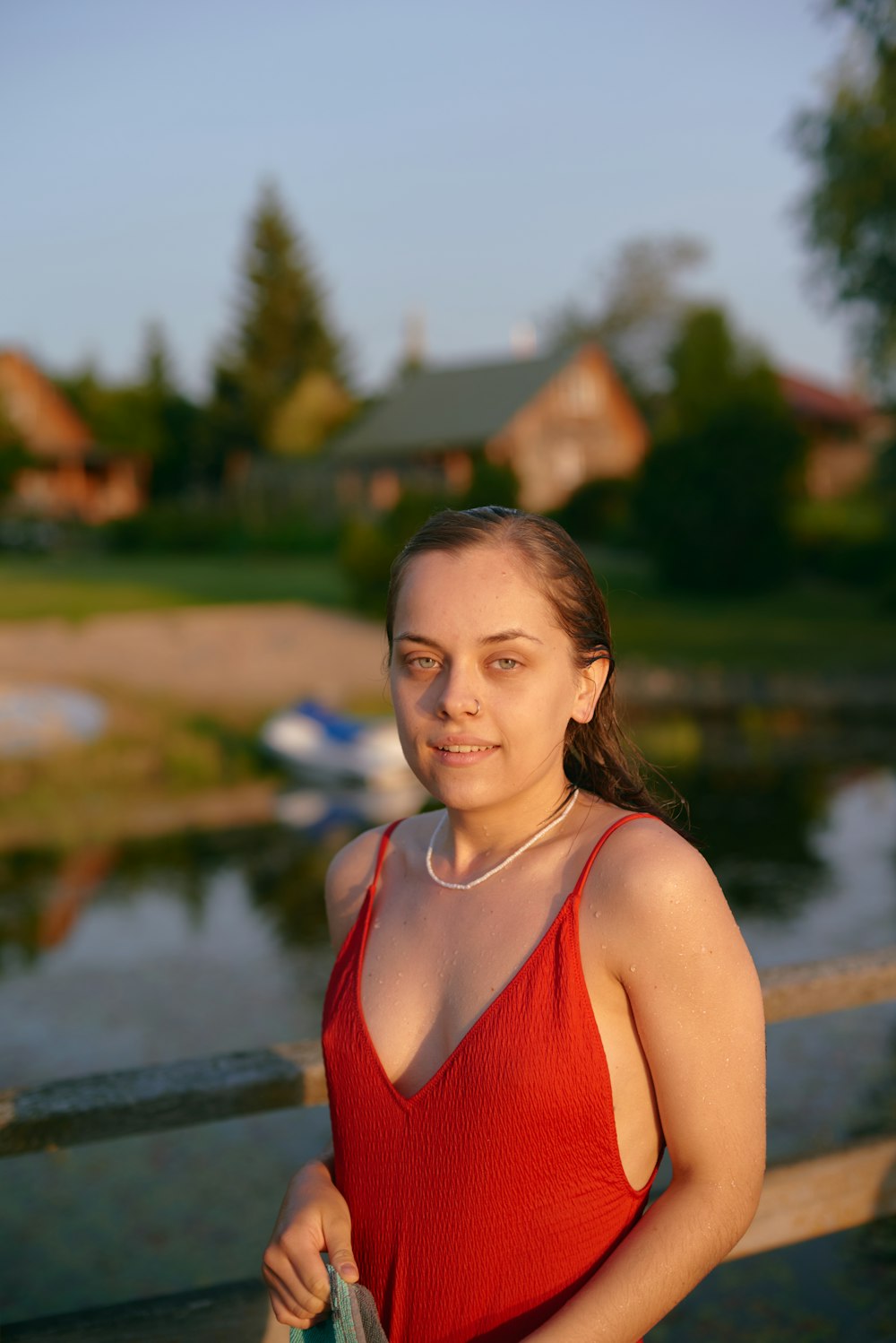 a woman in a red dress standing by a lake