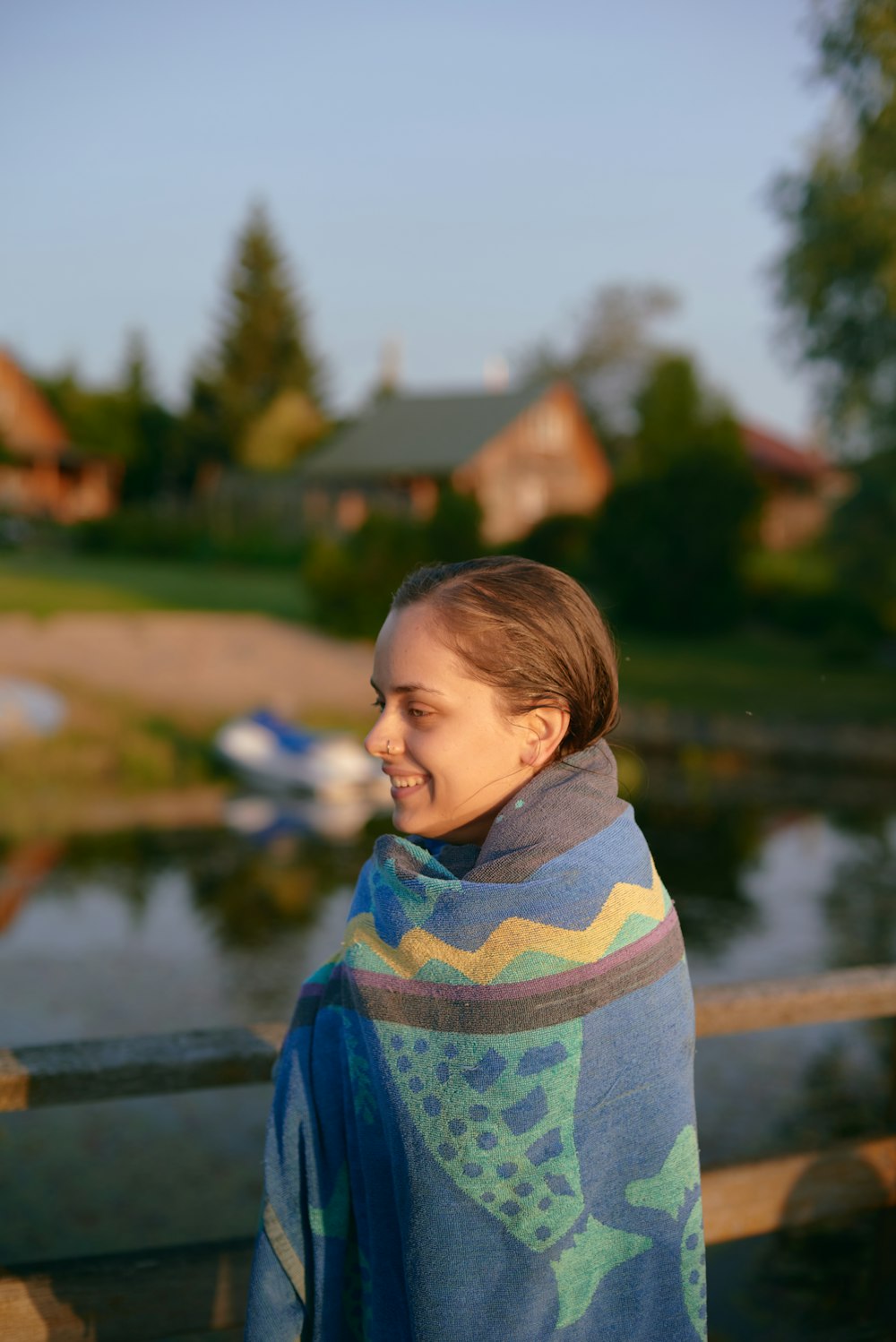 a woman wrapped in a blanket looking out over a lake