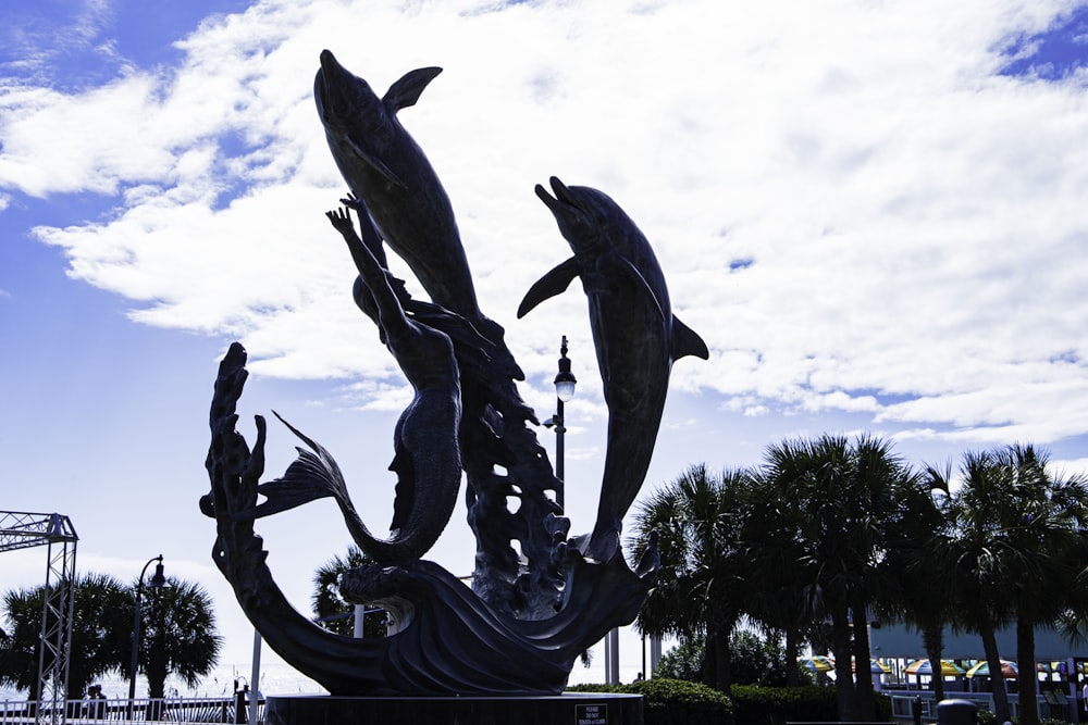 a statue of two dolphins and a boat in the water