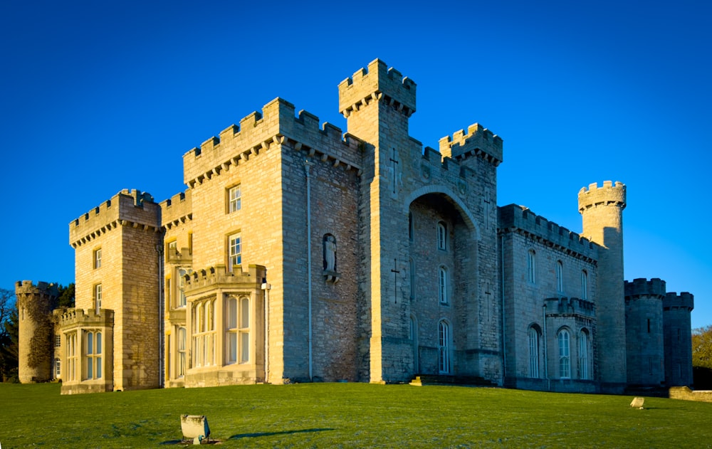 Un gran castillo como un edificio sentado en la cima de un exuberante campo verde