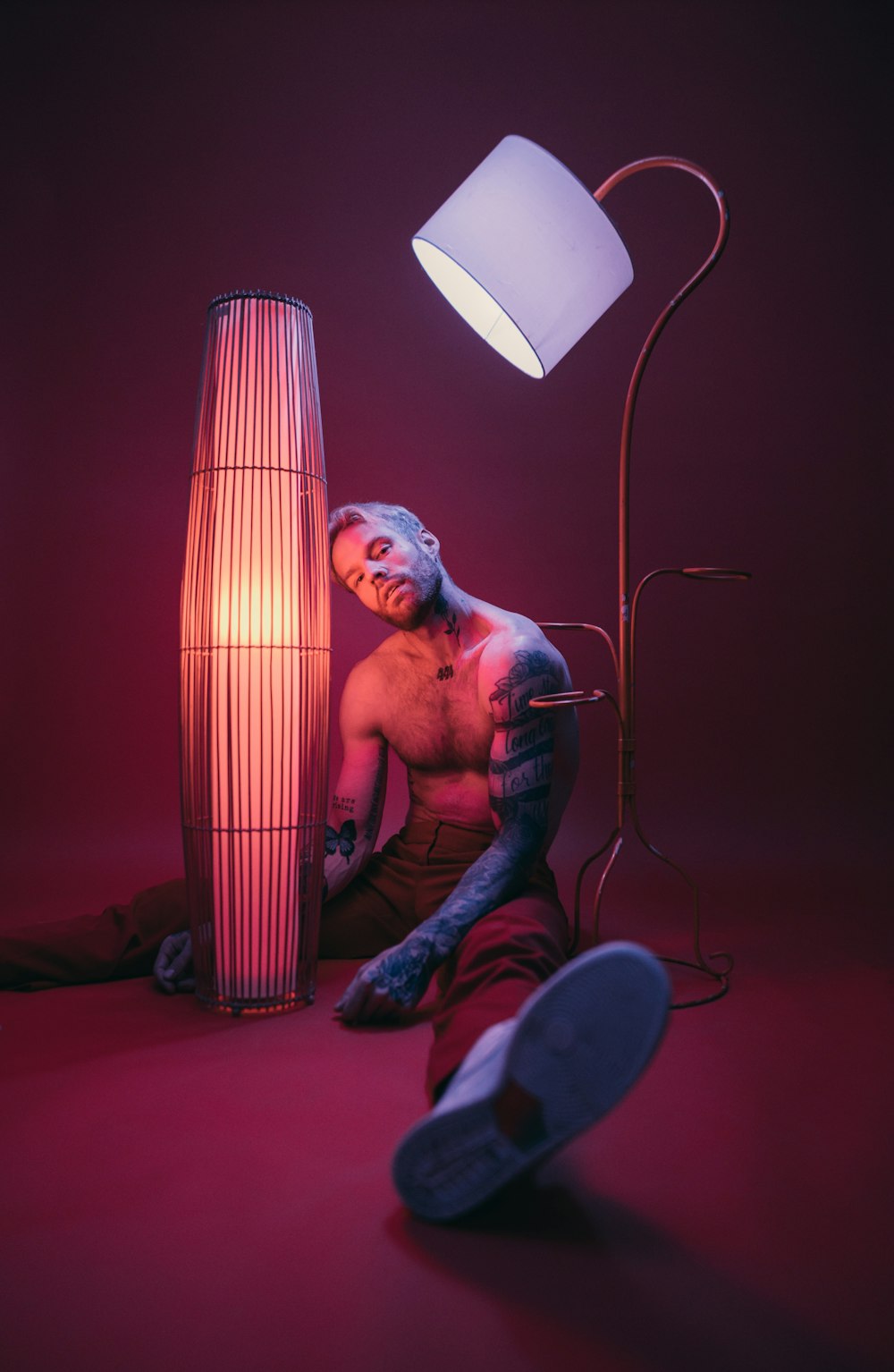 a man sitting on the floor next to a lamp