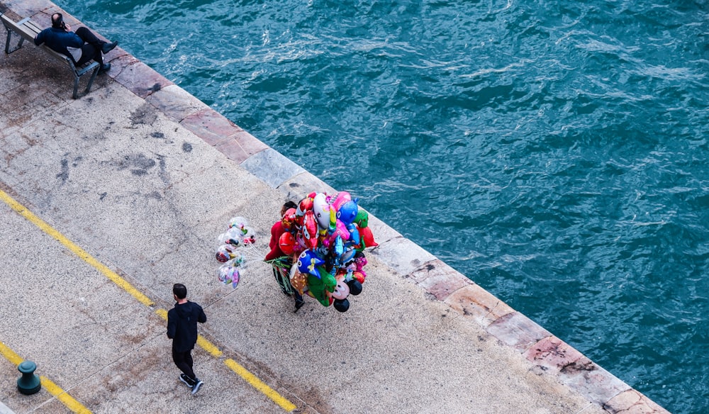 a group of people walking down a street next to a body of water