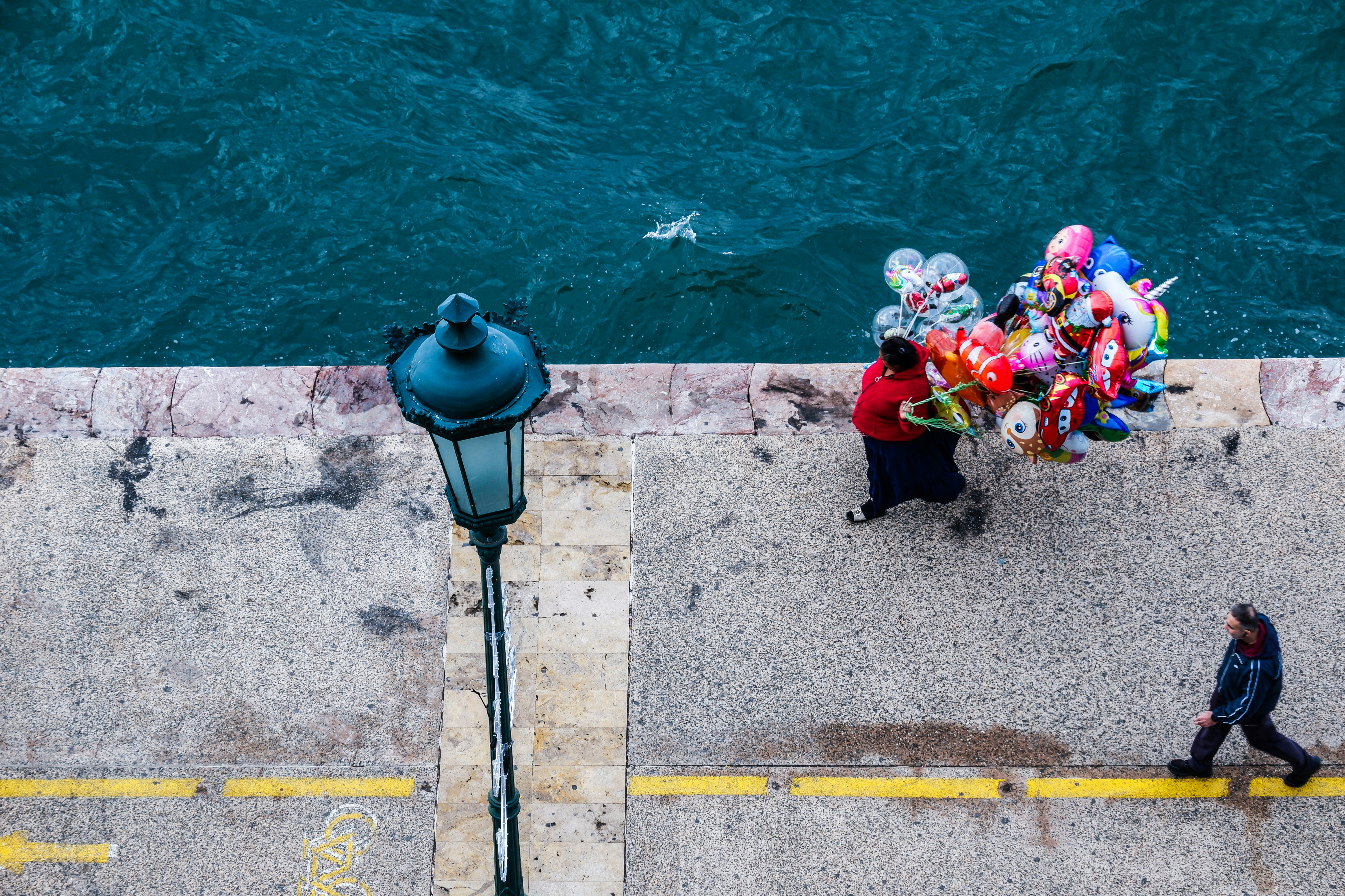 a person walking down a sidewalk next to a body of water