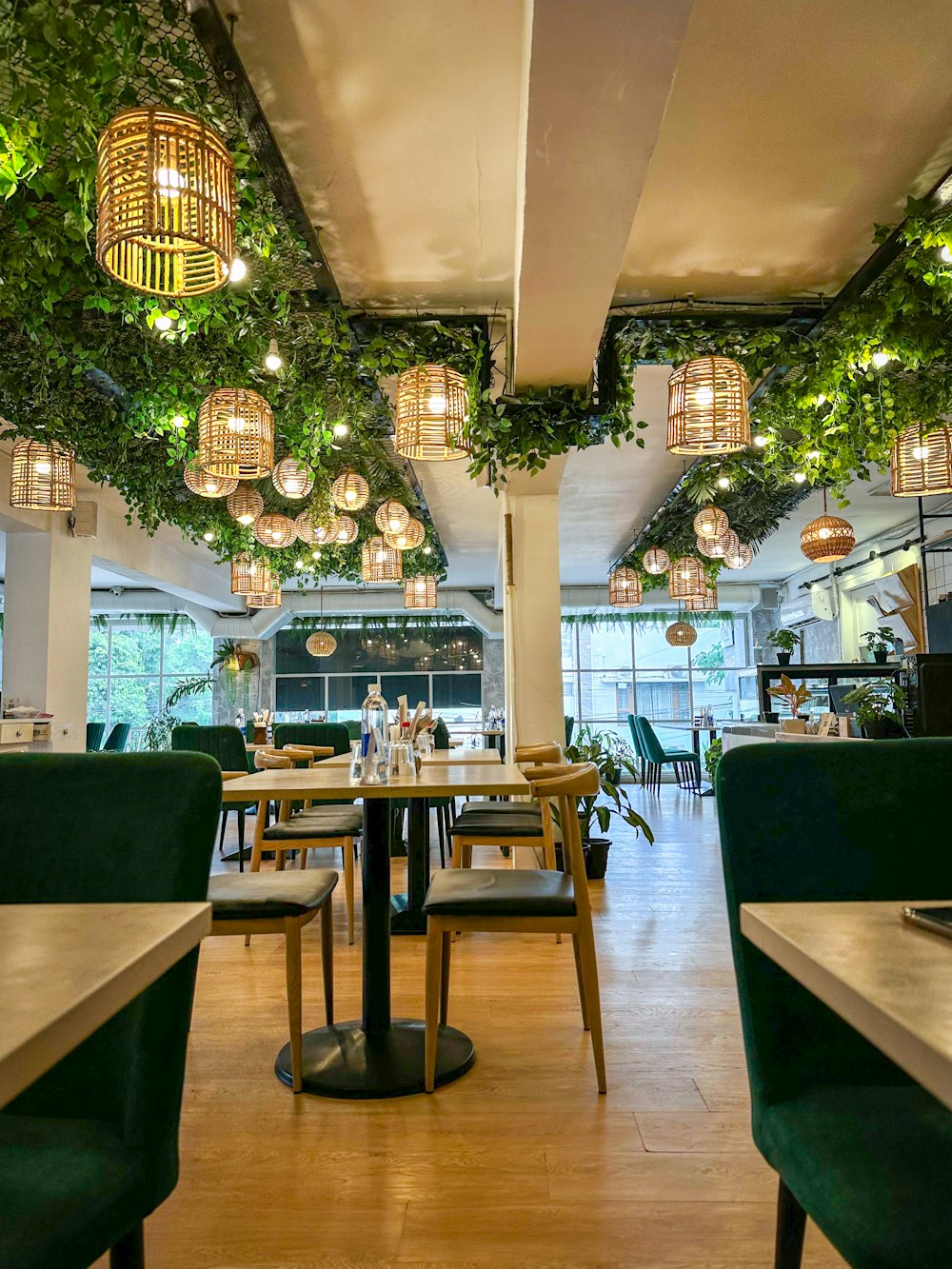 a restaurant with green chairs and plants hanging from the ceiling