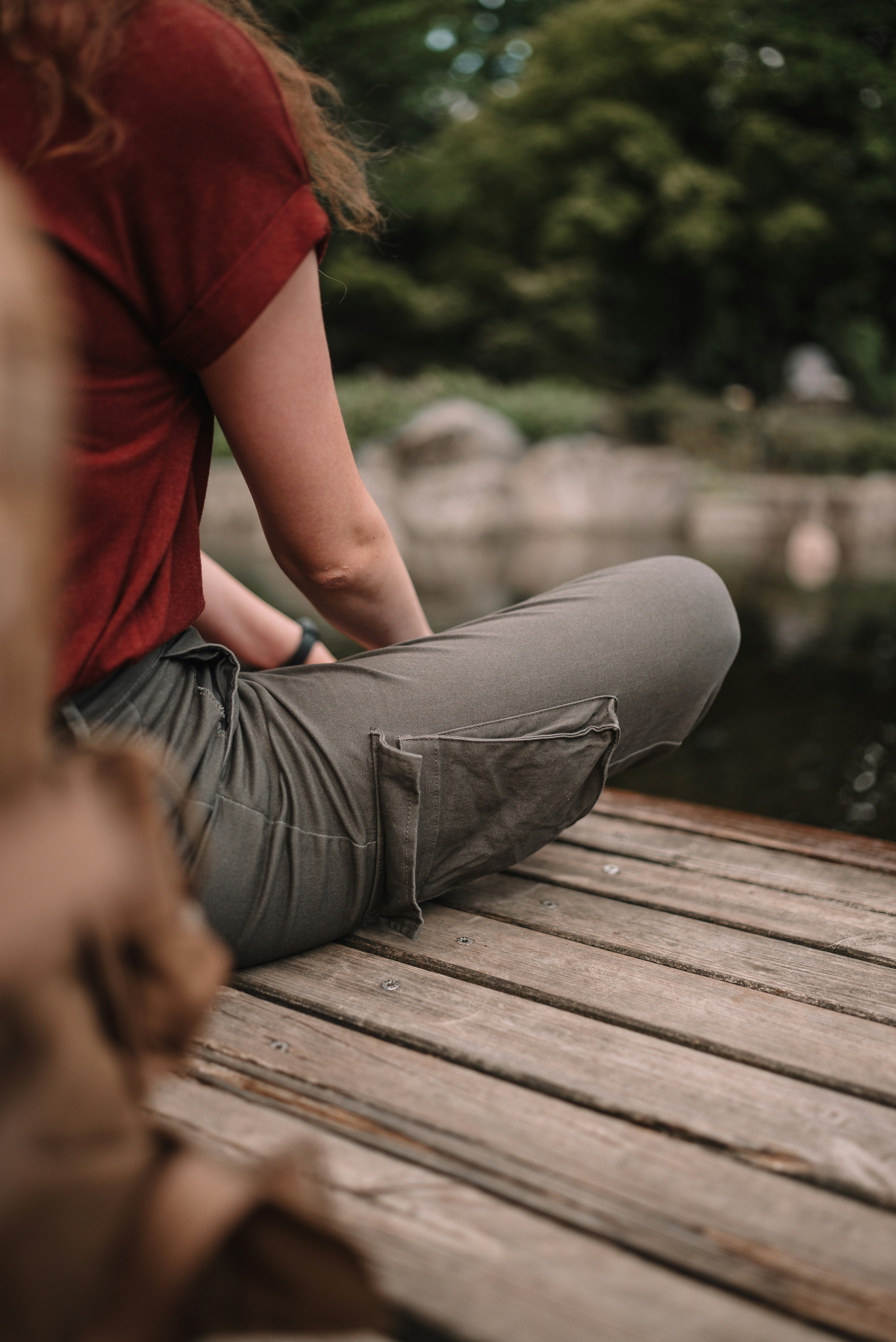 a woman sitting on a wooden dock next to a body of water