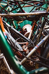 A tightly packed jumble of bicycle frames and parts with visible rust and wear, highlighting a collection of old or possibly abandoned bicycles.