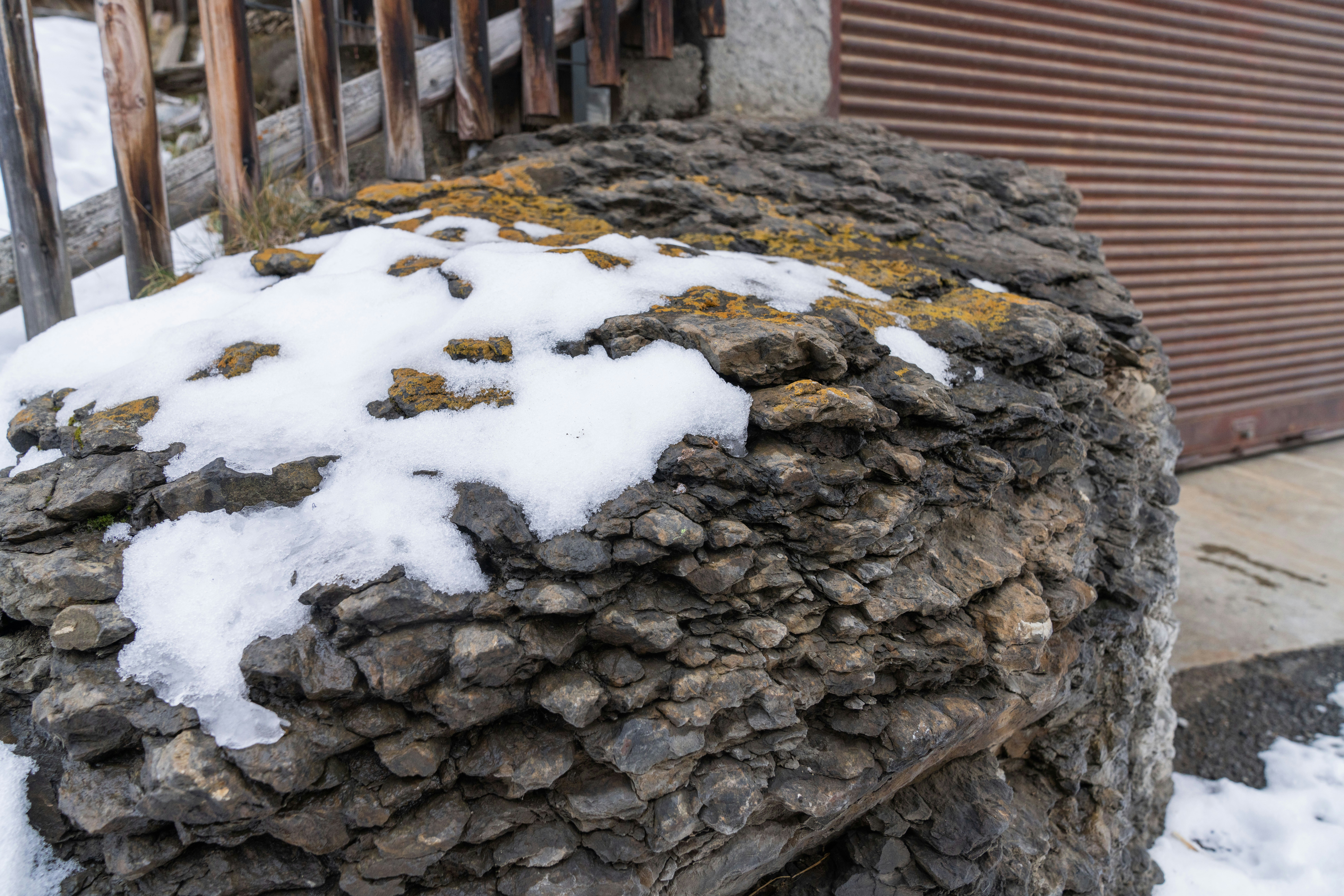 a pile of rocks covered in snow next to a building