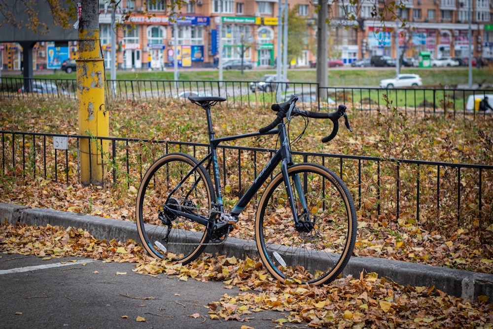 a bicycle parked on the side of a road next to a fence